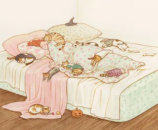 Several cats napping on a cozy bed with Halloween toys