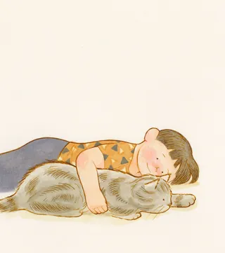 Child cuddling a gray cat while lying down
