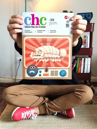 Hands holding Ciencia Hoje das Criancas magazine with cartoon woodlouse cover