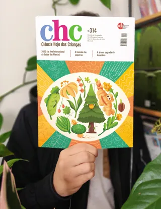 Person holding Ciencia Hoje das Crianças magazine with plants and animals