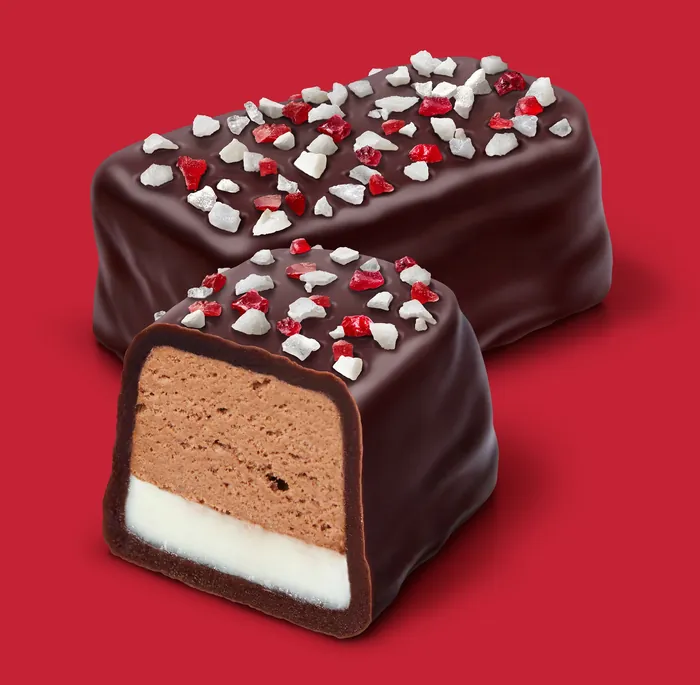 Chocolate-covered candies topped with red and white sprinkles on red background