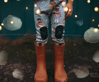 Child wearing patterned pants and brown boots with string lights