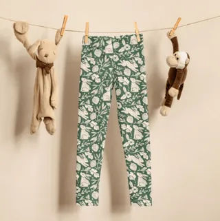 Children's leggings with green floral bunny pattern hanging on a line