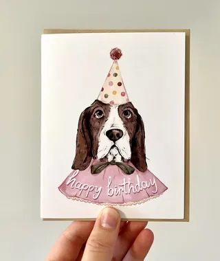 Illustration of hound dog in birthday hat and cape by Fox and Fables