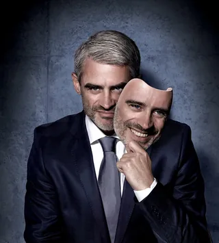 Man in suit holding a smiling face mask, artwork by Frank Neidhardt