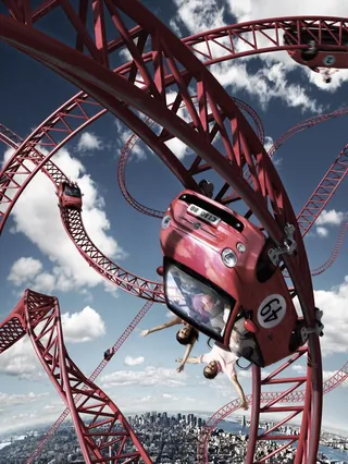 Red car on twisting rollercoaster track above city by Frank Neidhardt
