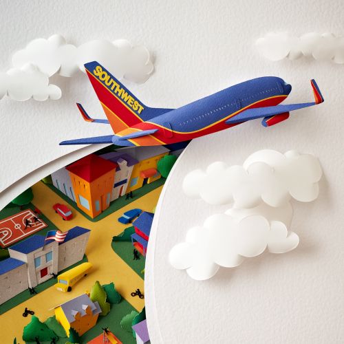 Paper sculpture image of a SouthWest Airlines plane cutting through the sky and clouds