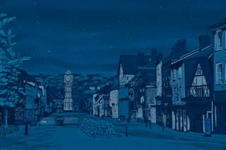 Night view of a historic street with a clock tower and old buildings.