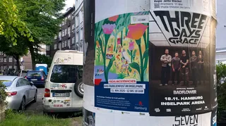Posters on pole with parked cars and urban street background