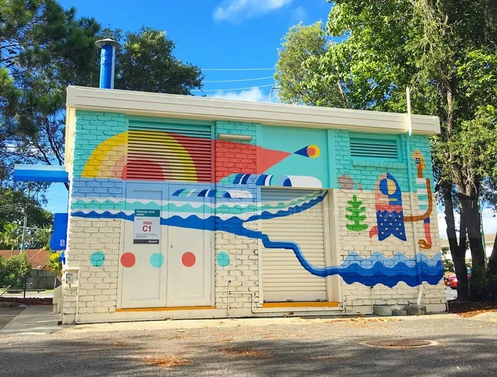 Colorful mural with waves and rainbow shapes on a building by Go Suga