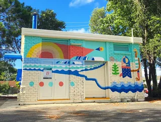 Colorful mural with waves and rainbow shapes on a building by Go Suga