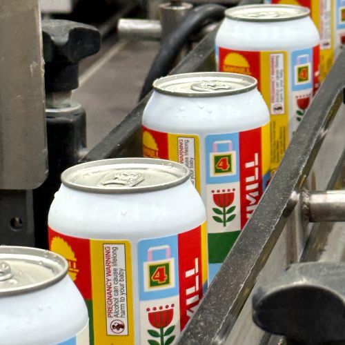 Soda cans with floral design on a production line by Greg Straight