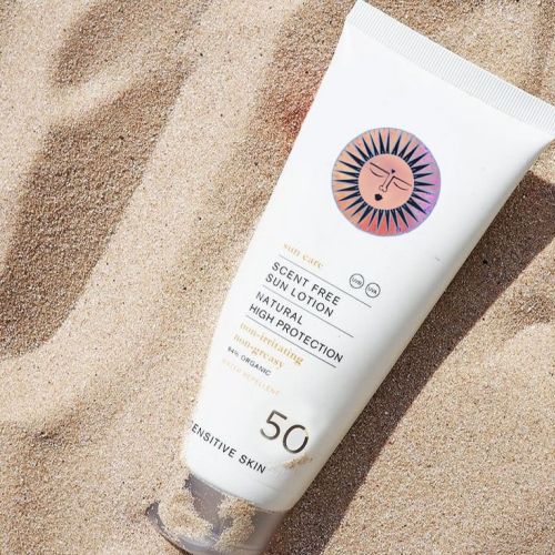 Sunscreen tube labeled SPF 50 on sand by Hannah Davies