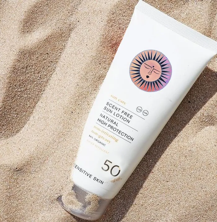 Sunscreen tube labeled SPF 50 on sand by Hannah Davies