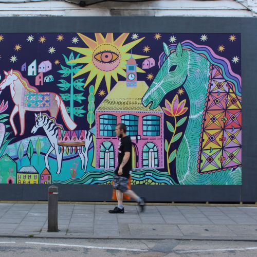 Colorful mural depicting horses, a house, and a sun by Hannah Davies