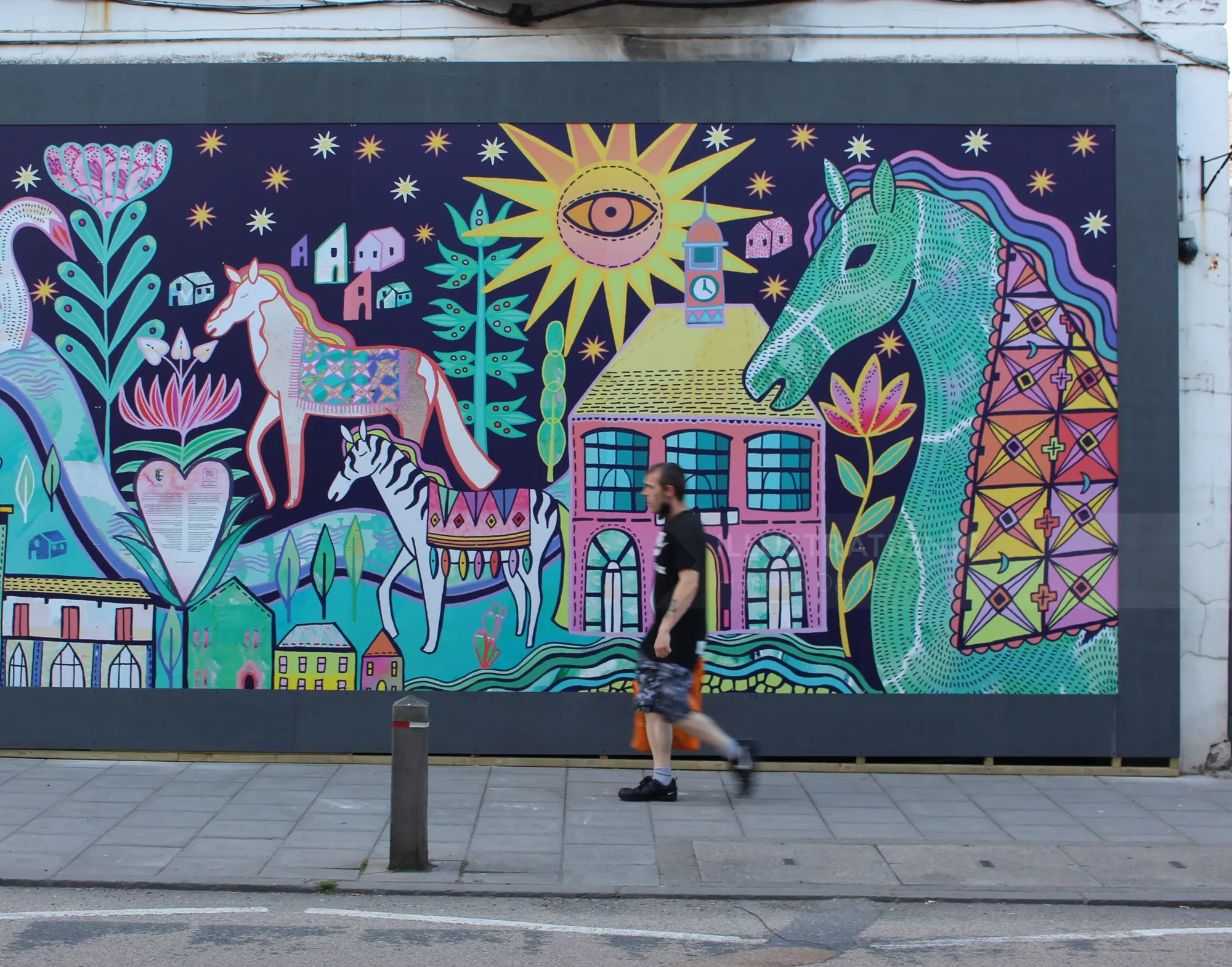 Colorful mural depicting horses, a house, and a sun by Hannah Davies