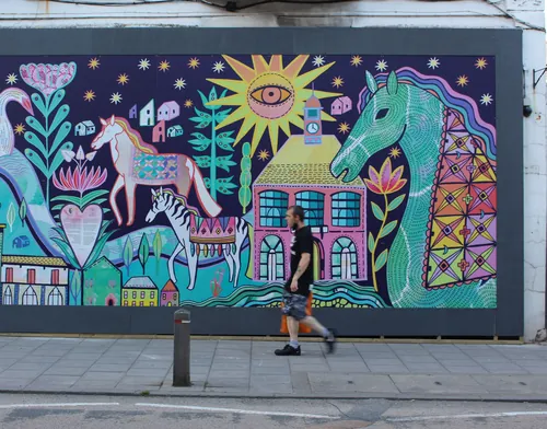 Colorful mural depicting horses, a house, and a sun by Hannah Davies