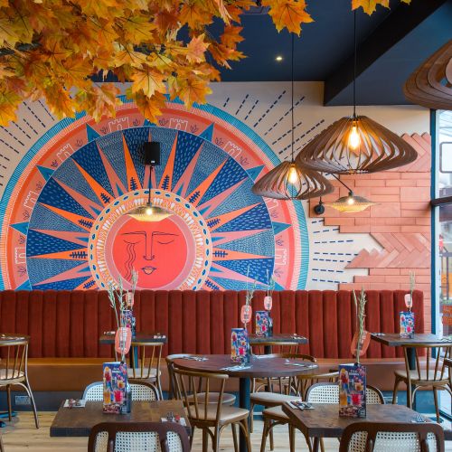 Colorful restaurant interior with sun mural and autumn decor