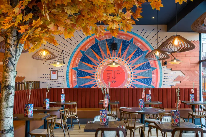 Colorful restaurant interior with sun mural and autumn decor