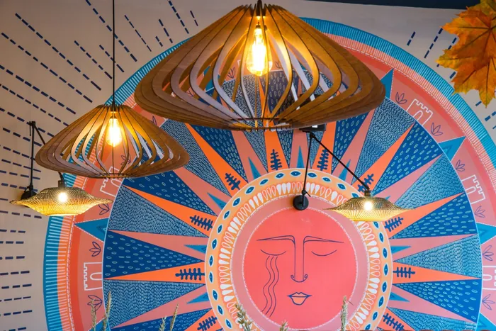 Colorful mural with a sun face and hanging wooden light fixtures