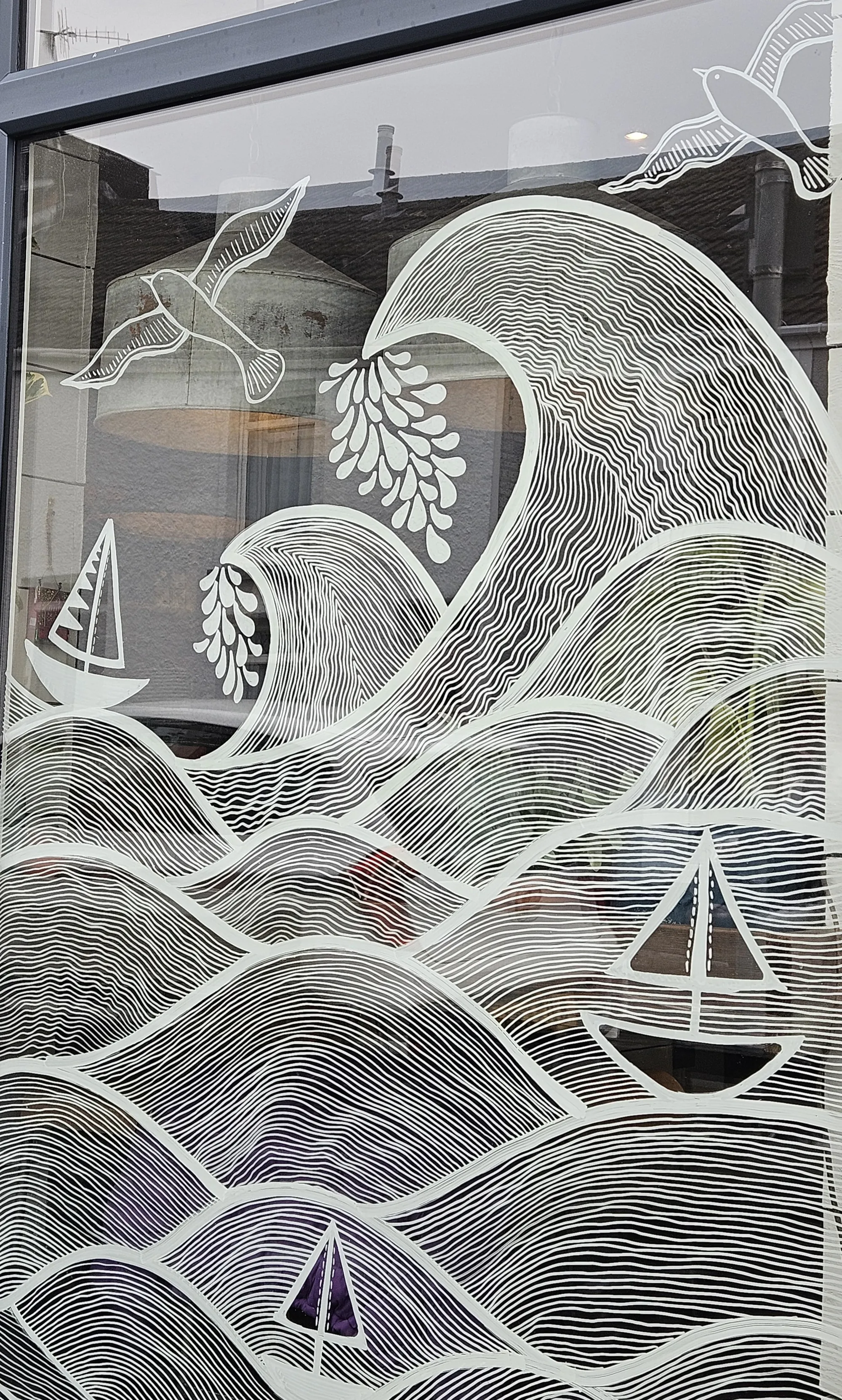 White line art mural of waves, birds and sailboats on window