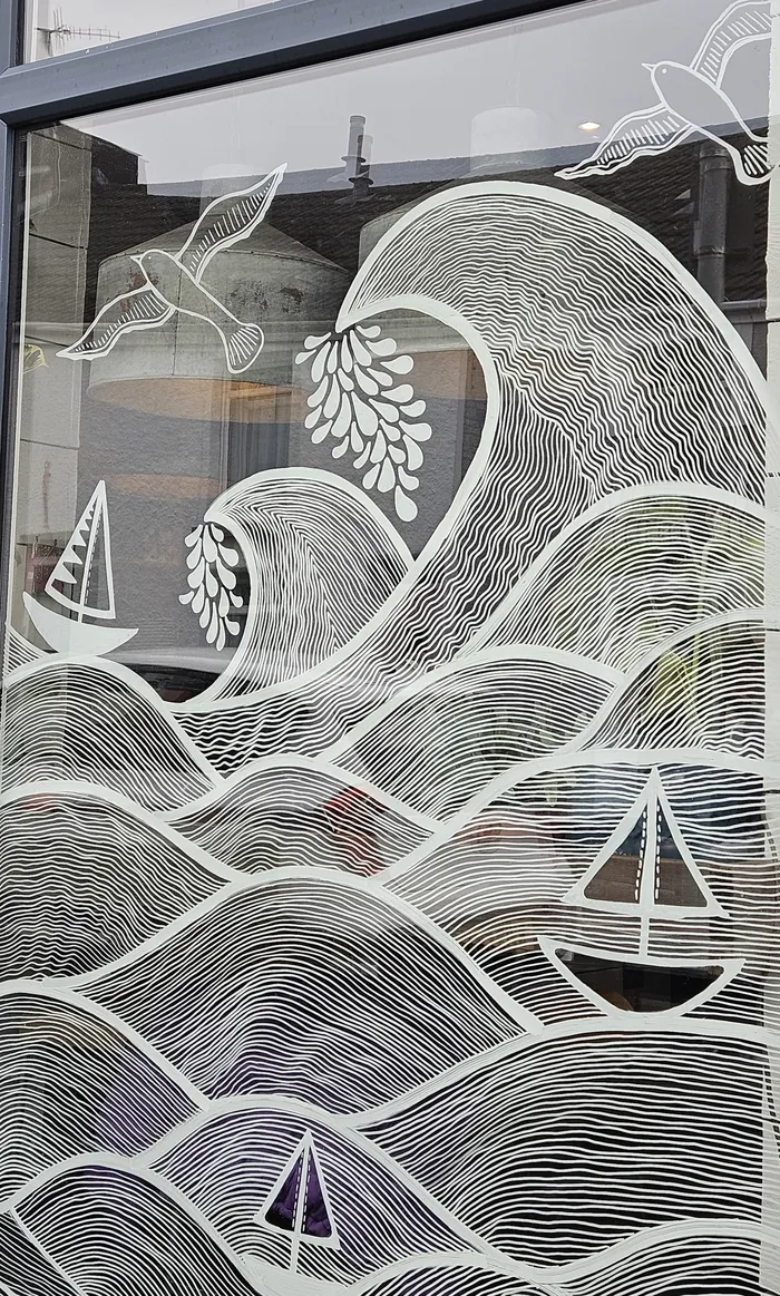 White line art mural of waves, birds and sailboats on window