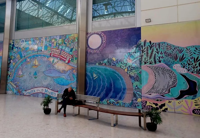Mural with ocean waves and wildlife, woman sitting on bench below
