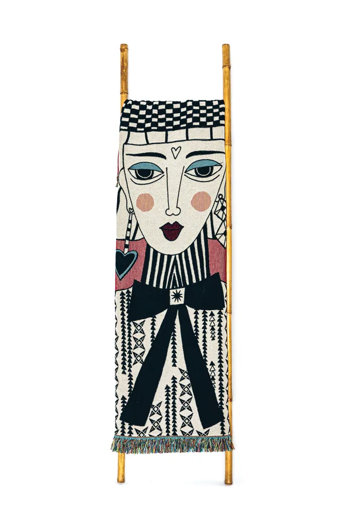Textile wall hanging with stylized human face and geometric designs