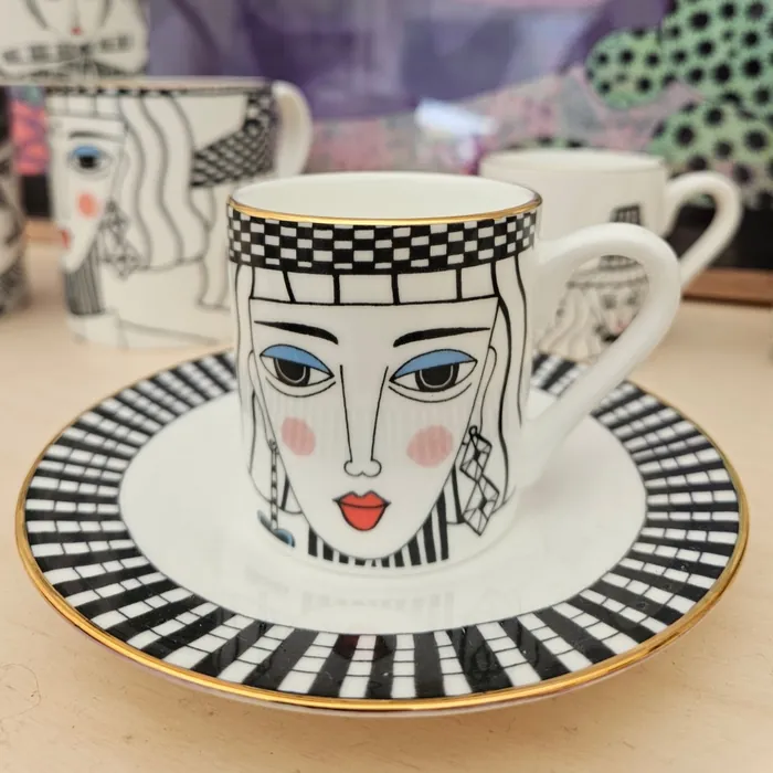 Coffee cup and saucer with black and white stylized female face artwork