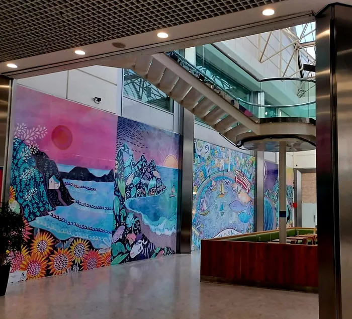 Vibrant mural paintings on walls inside modern building with stairs and seating