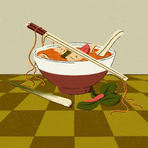 Bowl of noodle soup with chopsticks, spoon, and vegetables on checkered surface