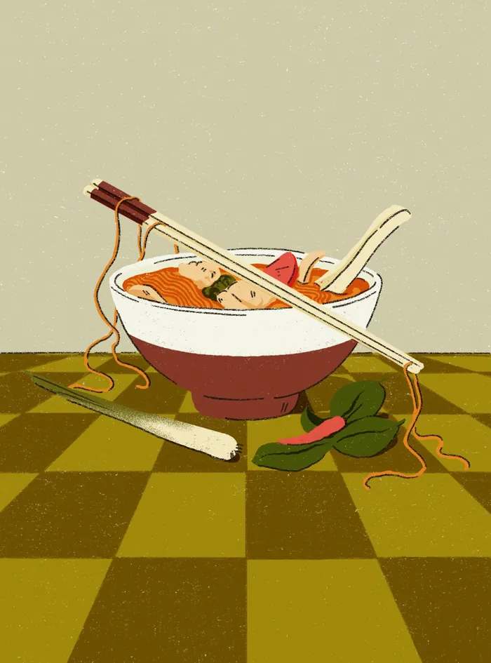 Bowl of noodle soup with chopsticks, spoon, and vegetables on checkered surface