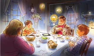 Family of four sitting around a dining table having dinner indoors