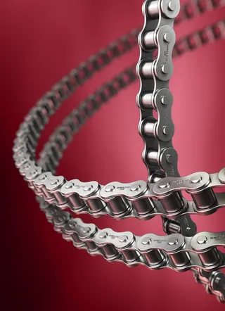 Close-up of metal roller chain links on red background