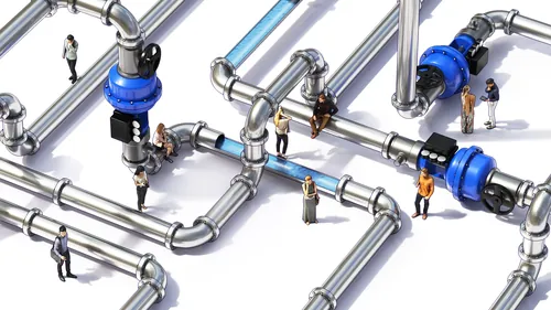 Tiny people interacting around large metal water pipes and valves.