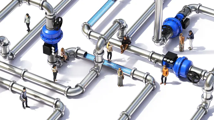 Tiny people interacting around large metal water pipes and valves.
