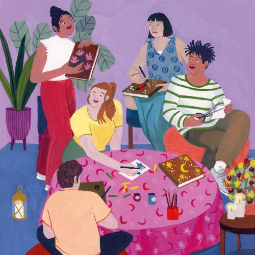 Four people reading and writing around a pink table with plants and lantern
