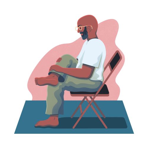 Man sitting cross legged on a folding chair wearing glasses
