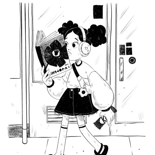 Young girl with headphones reading book at subway station platform