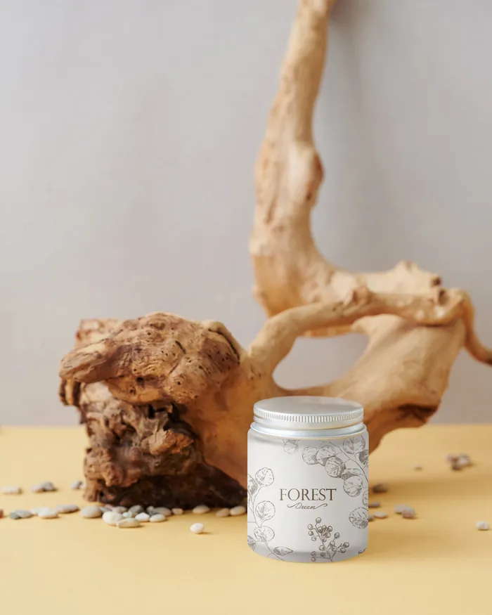 White Forest scented candle jar beside natural wood piece and scattered seeds