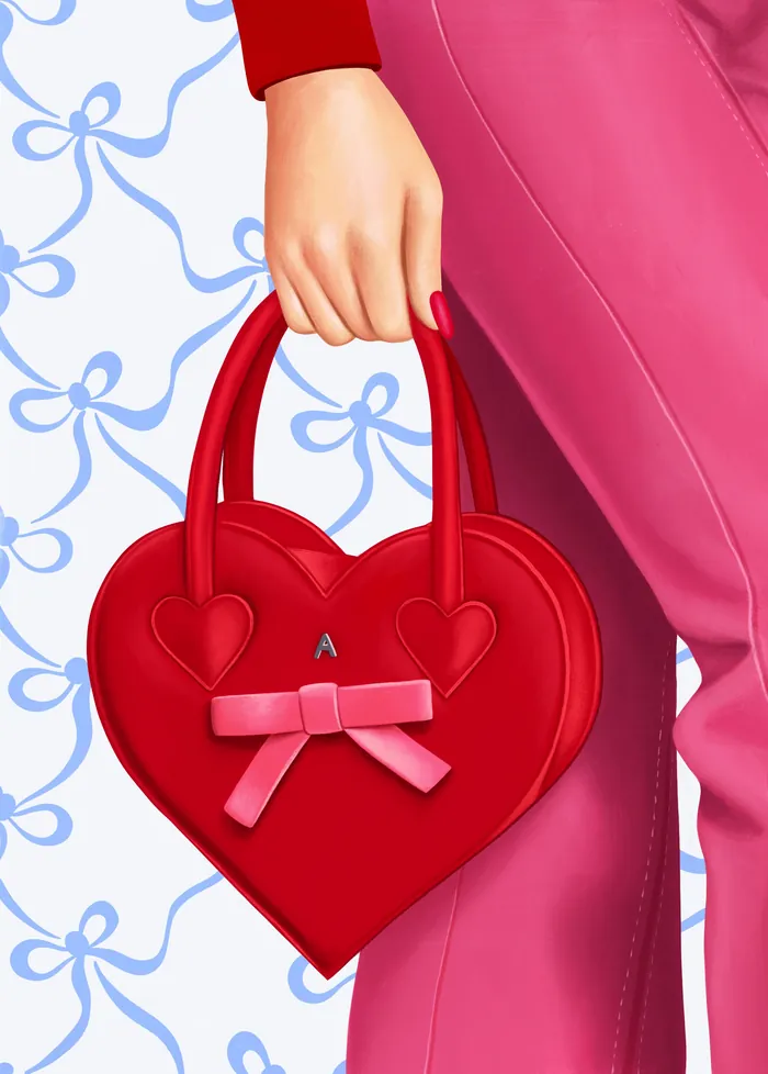 Hand holding red heart-shaped handbag with pink bow detail.