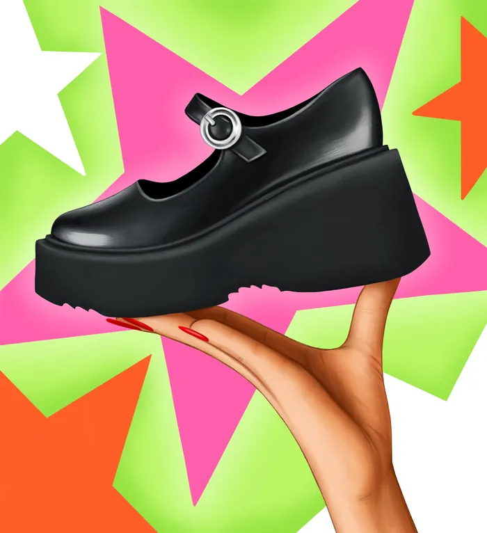 Hand holding black platform Mary Jane shoe in front of colorful stars