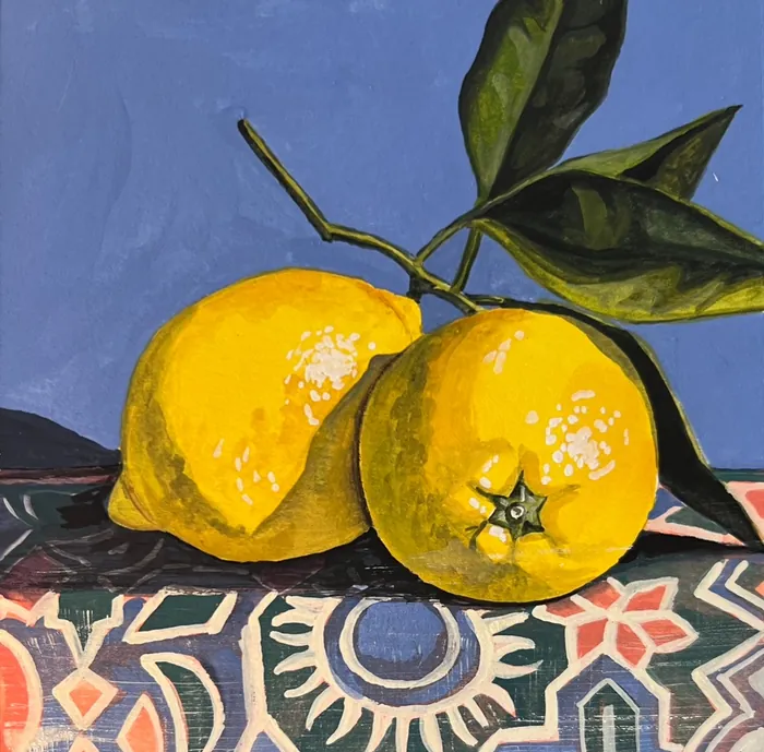 Two yellow citrus fruits with leaves on colorful patterned cloth
