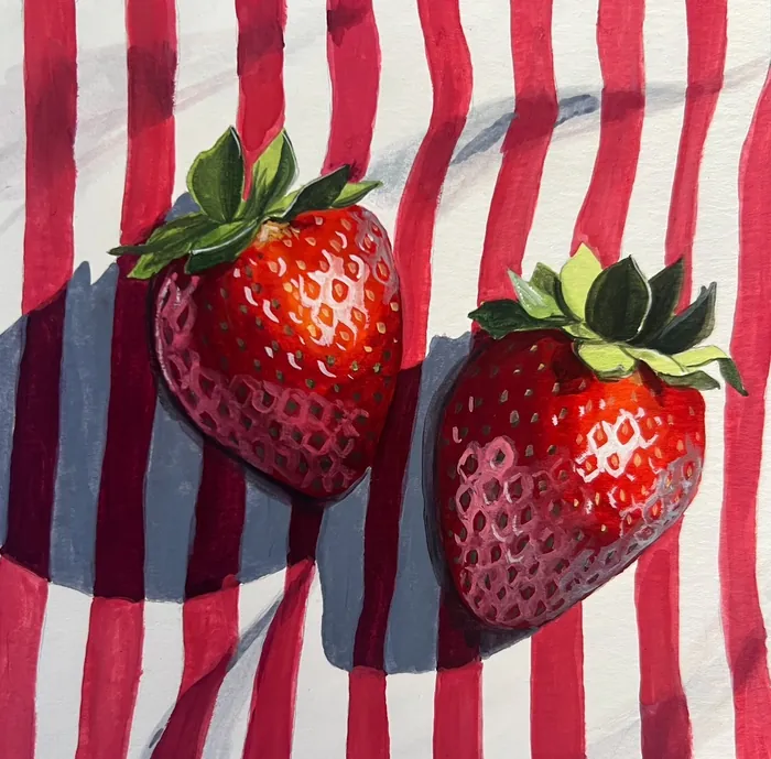 Two strawberries on red and white striped cloth casting shadows