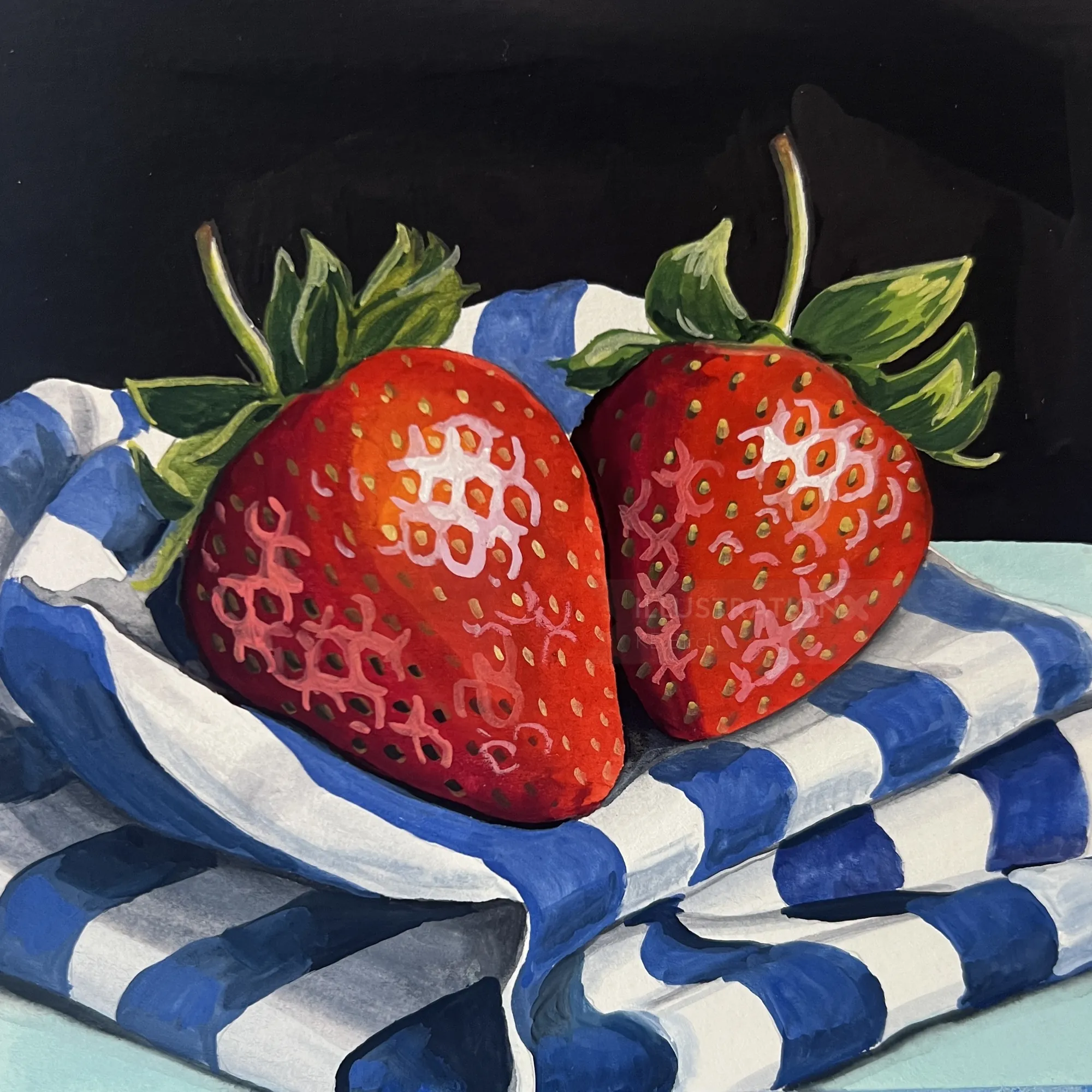 Two ripe strawberries on blue and white striped fabric