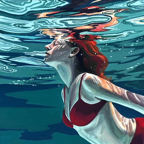 Woman with red hair swimming underwater in red swimsuit