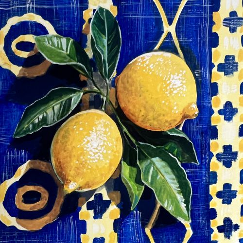 Two ripe yellow lemons with green leaves on a decorative blue and yellow surface