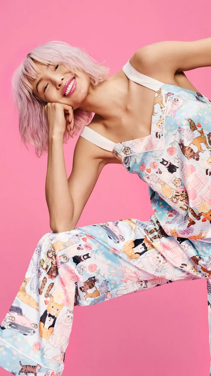 Smiling woman with pink hair in colorful overalls by Karen Mabon