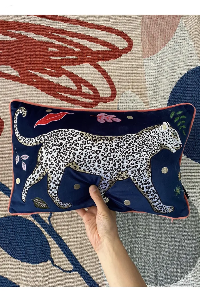 Hand holding pillow with printed leopard on navy blue background