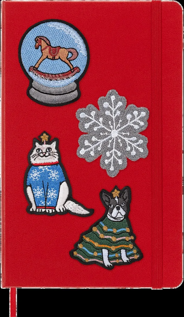 Red notebook with holiday-themed patches of rocking horse, snowflake, and cats